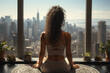 © sofiko14 - Back view of african woman practicing yoga sitting in the lotus position against the background of a panoramic window with an urban view