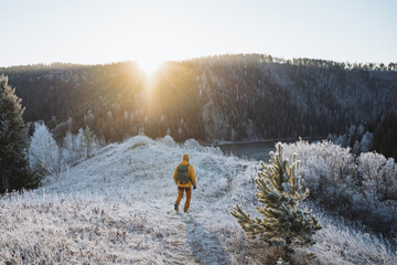 Sticker - Man in the mountains, rear view of guy walking with backpack on the road, mountain peak, sunrise over ridge, winter morning.