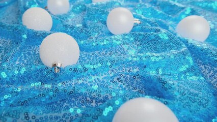 Wall Mural - Christmas light blue background. Glass Christmas bauble on shiny sequin fabric. Slow motion. New Year decoration