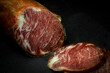 Close up view of cut of delicious Iberian lomo embuchado sausage cured in winery in Spain on black background with copy space