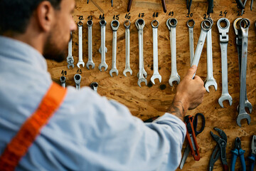 Wall Mural - Close up of mechanic using wrench while working at repair shop.