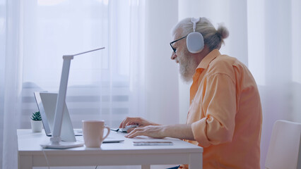 senior man plays a video game on his laptop, upset about losing, yet committed to his retirement hob
