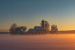 Bavarian church of Raisting with trees and snow and mist during winter and sunset, snow field in the foreground, blue sky day, Bavaria Germany.