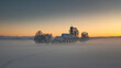 Bavarian church of Raisting with trees and snow during winter and sunset, snow field in the foreground, Bavaria Germany.