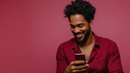 Wall Mural - A handsome dark skin man is looking at a smartphone screen. Pink monochrome studio background.