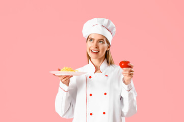Wall Mural - Female chef with tasty pasta and tomato on pink background