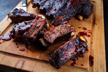 Wall Mural - Traditional barbecue burnt chuck beef ribs marinated with spicy rub and served as close-up on a rustic wooden board