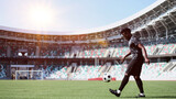 Fototapeta Sport - African American man playing football on the stadium field. A man runs with a soccer ball across the field.