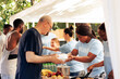 © DC Studio - Young volunteers at local center giving complimentary nourishment to diverse group of homeless people benefiting from charitable food campaign. Charity workers share free meals to the hungry and poor.