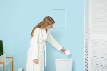 Wall Mural - Young woman putting paper roll on toilet tank in restroom