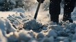 A person is seen shoveling snow with a shovel. This image can be used to depict winter activities or clearing snow from driveways and sidewalks