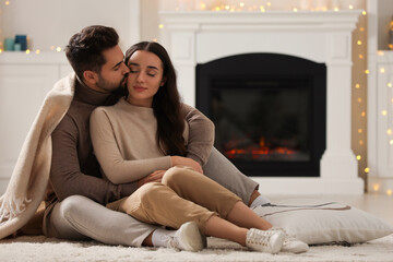 Poster - Young man kissing his girlfriend on soft carpet at home. Space for text