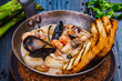 Mixed seafood saute served with toasted bread in a pan