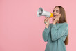 Special promotion. Young woman shouting in megaphone on pink background, space for text