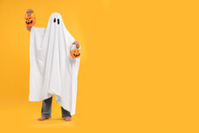 Woman In White Ghost Costume Holding Pumpkin Buckets On Yellow Background, Space For Text. Halloween Celebration