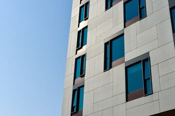 The exterior wall of a contemporary commercial style building with aluminum metal composite panels and glass windows. The futuristic building has engineered diagonal cladding steel frame panels. 