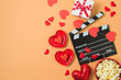 Happy Valentine's day and romantic movie concept with  movie clapper board, heart shapes and popcorn on trendy background. Top view, flat lay