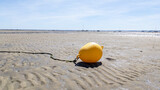 Fototapeta Tęcza - Yellow buoy on the sand beach on the shoreline in low tide