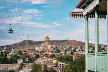 Wall Mural - View of the Sameba Cathedral, the Tbilisi ropeway, and a traditional Georgian wooden balcony in Tbilisi