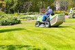 A gardener uses a tractor-type industrial lawn mower to cut the grass. Professional Gardening Details