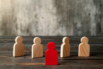 Red wooden figures stand out from the crowd of wooden figures