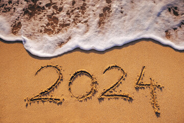 Wall Mural - Happy New Year 2024 concept, lettering on the beach. Written text on the sea beach at sunrise.