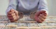 Hands Of Corrupt Female Manager In Handcuffs And US Dollars