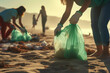 men and women in green top gloves collect garbage on sandy beach