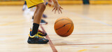 Fototapeta  - Horizontal image of young basketball player bouncing ball in training drill. Youth basketball team on training. Basketball training session for school kids. Junior-level basketball player in a game