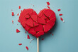 A broken heart on a stick with confetti close-up. Perfect for illustrating heartbreak, breakup, sadness, or emotional pain in designs, valentine day, or greeting cards.
