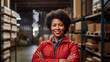 Black woman Logistic worker with no hat standing and smiling at the camera on a warehouse background