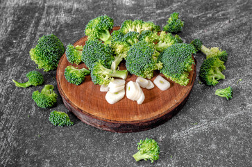 Wall Mural - Green broccoli and garlic - still life image of food background. Top view. Wooden natural round stand.