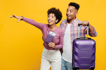 Traveler couple two friends family man woman wear casual clothes hold passport ticket bag isolated on plain yellow background. Tourist travel abroad in free time rest getaway. Air flight trip concept.