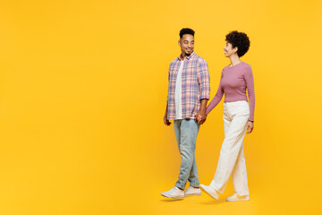 Wall Mural - Full body side view young couple two friend family man woman of African American ethnicity wear purple casual clothes together hold hand walk go stroll look camera isolated on plain yellow background