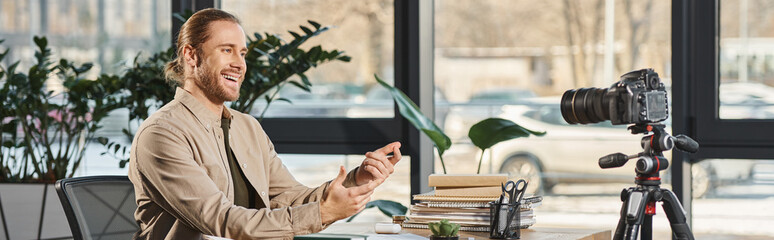 cheerful entrepreneur talking and gesturing in front of digital camera at workplace, banner