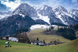 Zahmer Kaiser. View of mountain range in winter in Walchsee, Tyrol, Austria. Some houses and a snow cannon in the foreground in front of a green meadow
