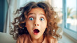  A child with curly hair and wide blue eyes shows a look of sheer amazement, her mouth open in a perfect 'o' of surprise