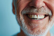 Elderly man with white teeth smiling on pastel blue background. Close up portrait of happy emotional bearded man