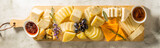 Fototapeta Tulipany - Cheese plate. Different types of cheese on a long wooden board. Horizontal banner