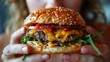 Close up shot of hands holding a mouth watering and irresistible burger, ready to take a bite