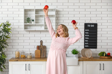 Poster - Happy young pregnant woman with apples in kitchen