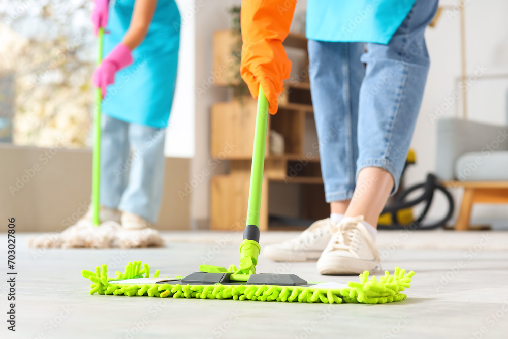 Female janitor mopping floor in room, closeup