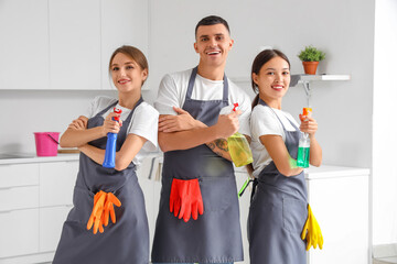 Canvas Print - Team of young janitors with bottles of detergent in kitchen