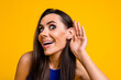 Photo of tricky excited woman wear blue top arm ear listening empty space isolated yellow color background