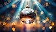 Glittering Disco Ball with Blue Rays. A glittering disco ball hangs suspended with radiant blue rays casting a festive atmosphere over a soft bokeh background