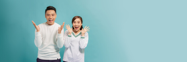 Wall Mural - Portrait of Asian couple with surprised and excited expression isolated on turquoise banner