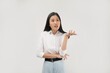 © Illhamt - A young Asian woman in a white shirt gestures with her hand raised, appearing to explain or emphasize a point in a bright, indoor environment during work hours