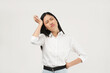 © Illhamt - A young Asian woman in a white shirt stands with her hand on her head, looking frustrated in an indoor setting with a white background, reflecting workplace challenges