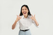 © Illhamt - An Asian woman in a white blouse raises both hands in the 'rock on' gesture while smiling widely. The plain white background emphasizes her fun and lively energy.