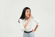 © Illhamt - An Asian woman in a white blouse leans forward with her hand cupped to her mouth, as if whispering or sharing a secret. She looks playful against a white background.